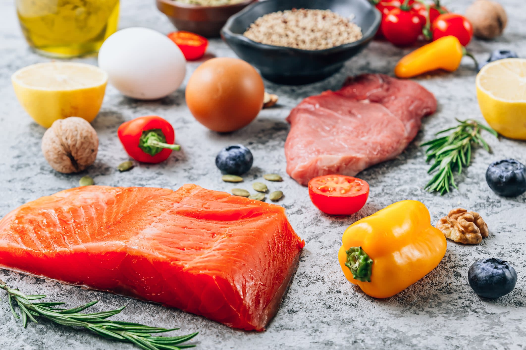 A collection of raw low FODMAP foods, including salmon, walnuts and yellow peppers