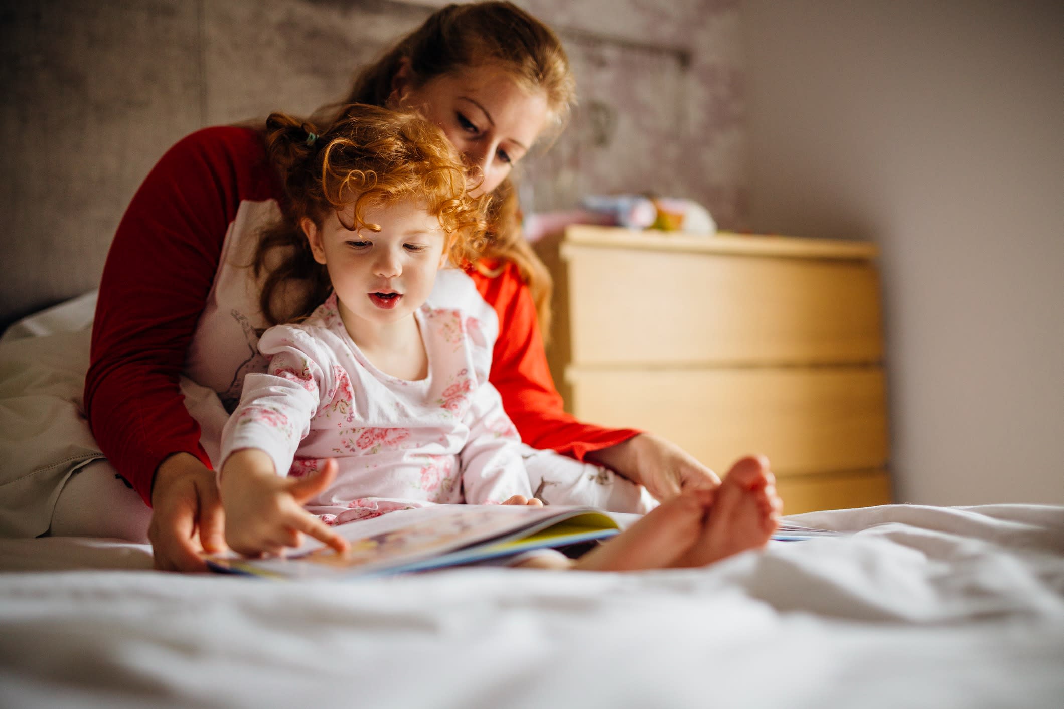Little girl reading a bedtime story with her Mother in her bed.