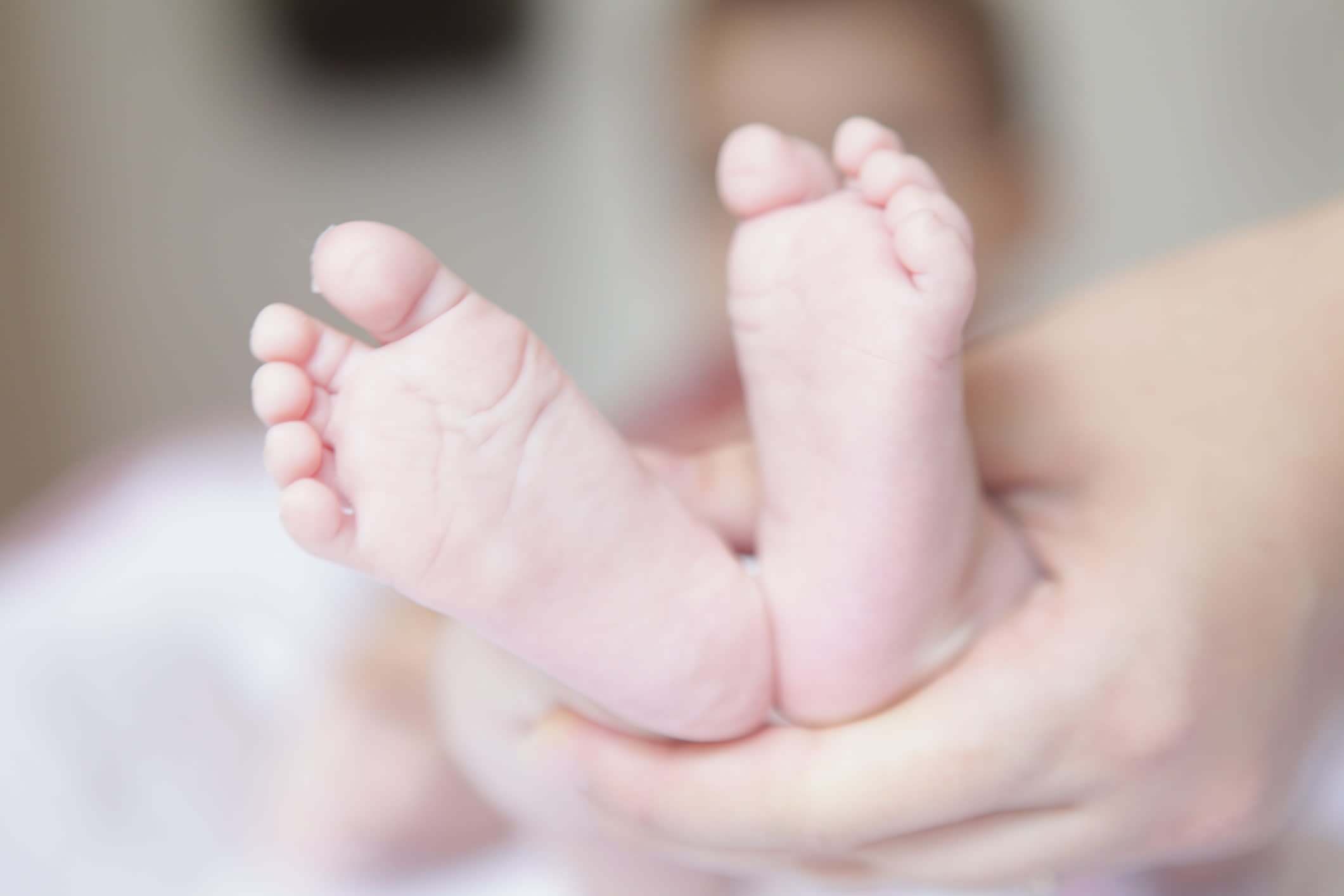 Close-up of a woman's hands holding a baby's feet