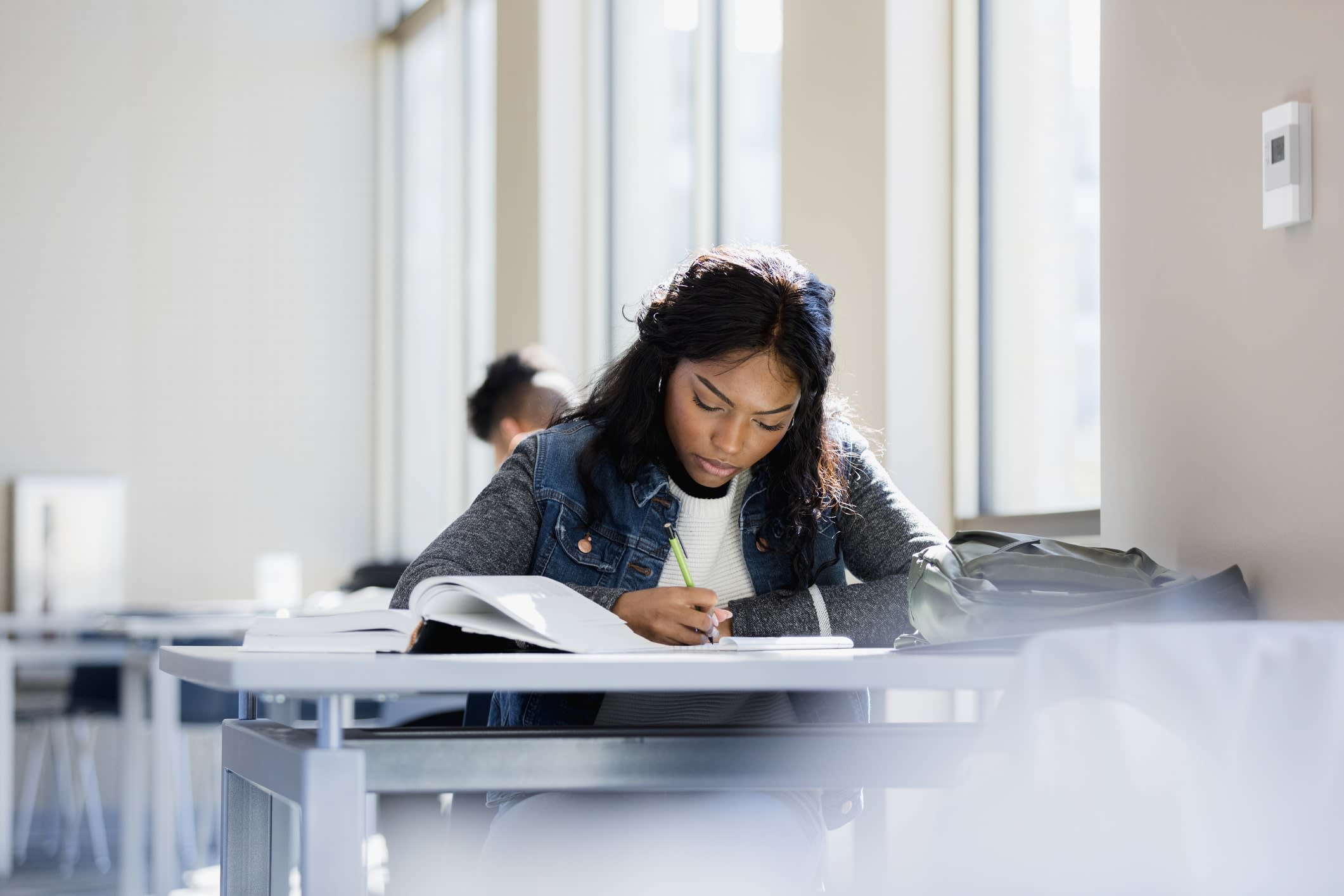 A focused young woman writing at a desk 