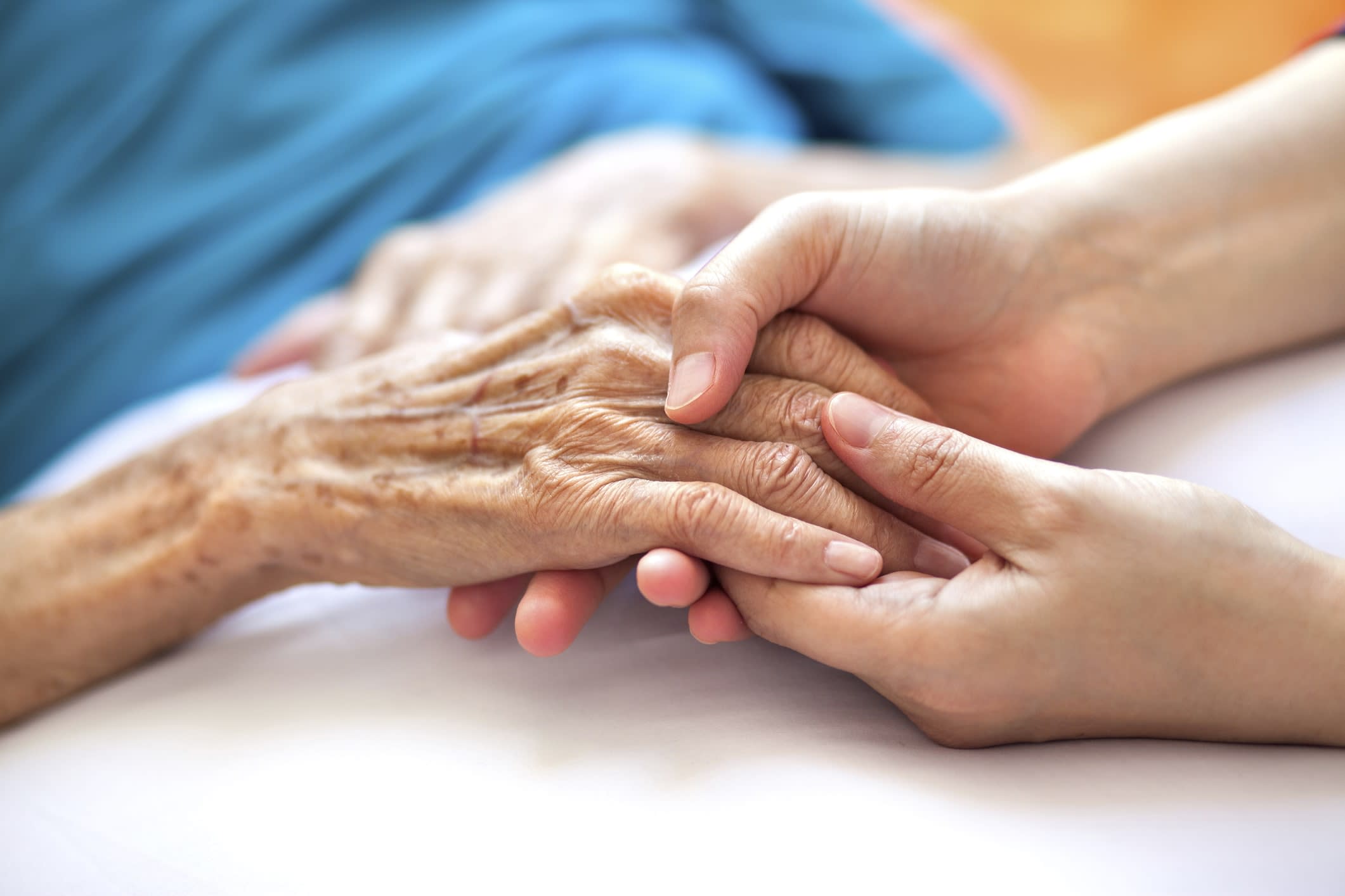 Close-up of a nurse holding the hand of an elderly woman