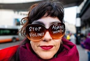 Woman wearing oversized sunglasses with the words 'Stop violence against women' on the lenses