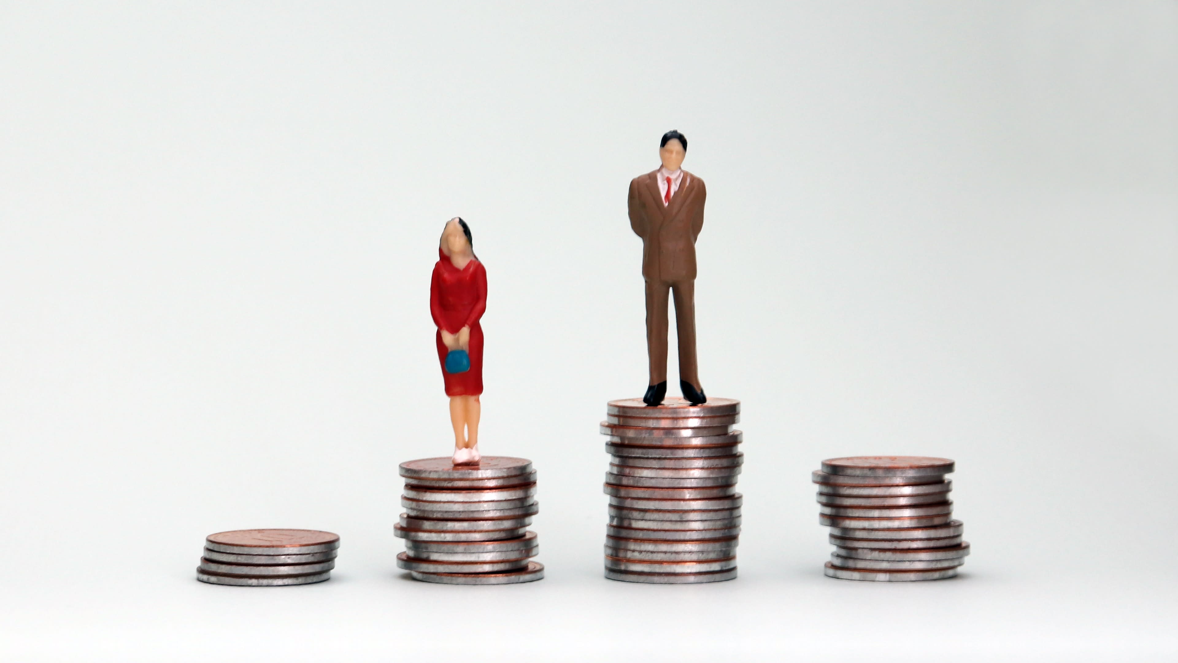 Female and male figurines standing on stacks of coins