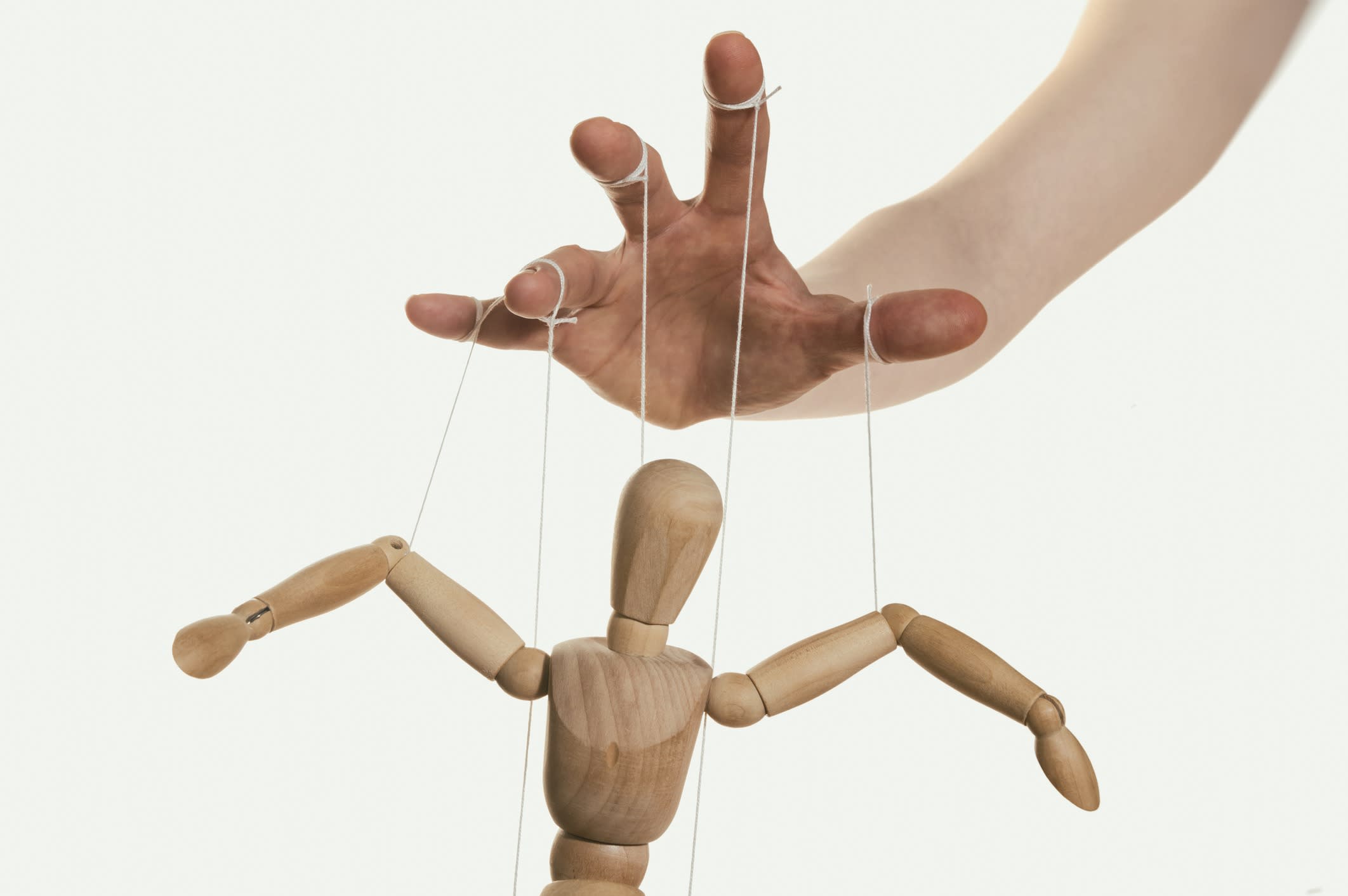 Concept of control. Marionette in human hand. Close-up.