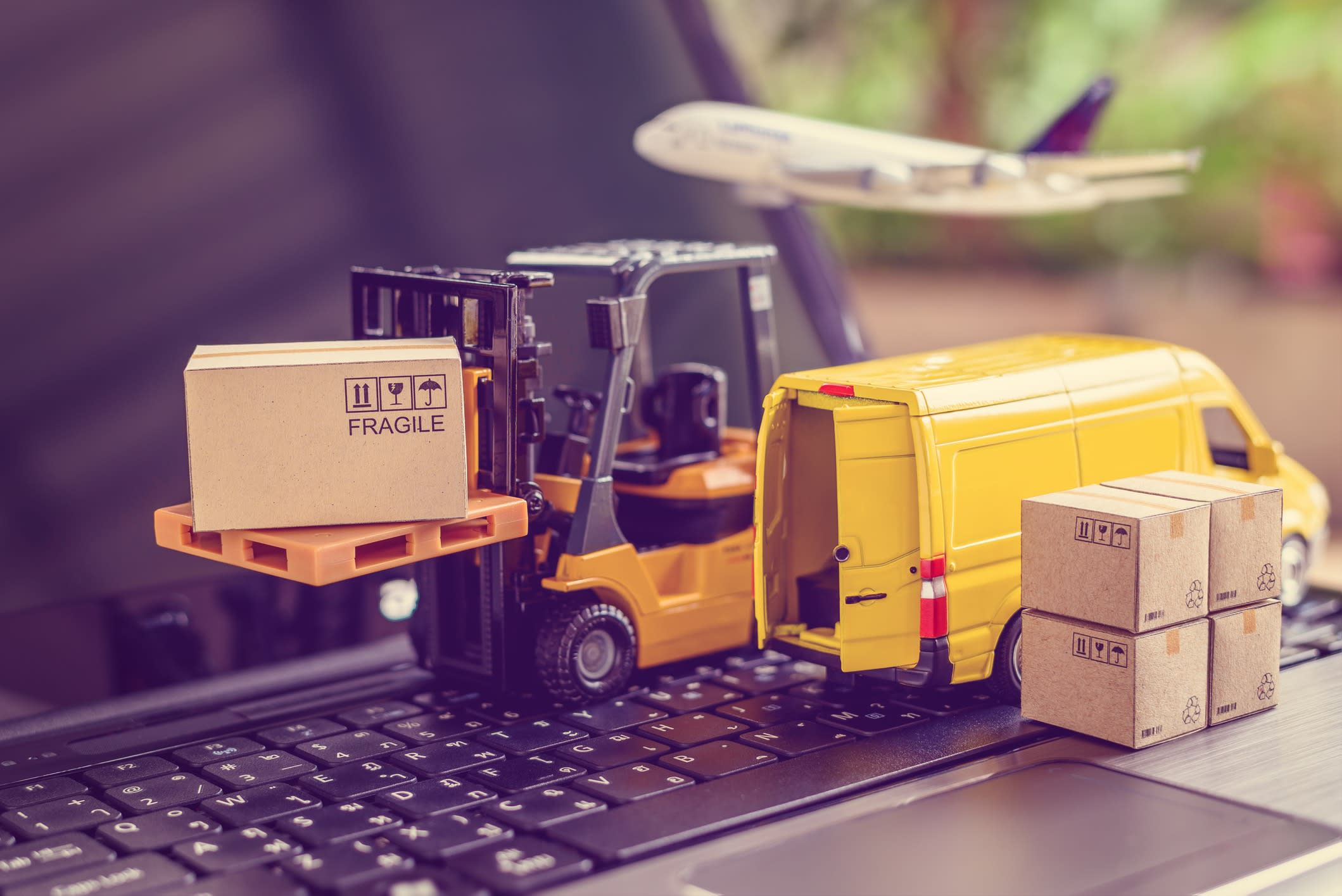 delivery service concept : Fork-lift truck moves a pallet with box carton. Van on a laptop computer