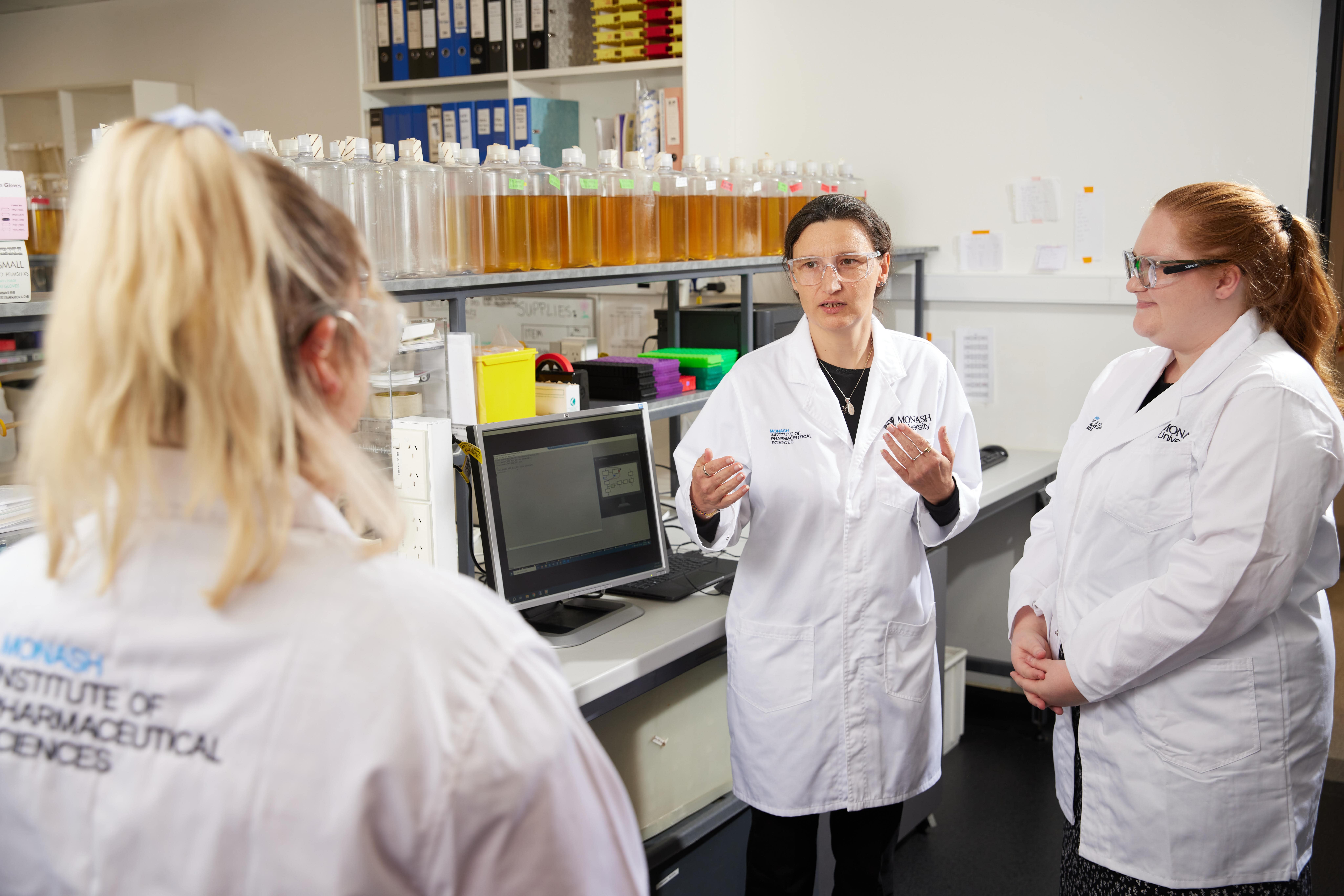 Associate Professor Cornelia Landersdorfer talks to two colleagues in a lab