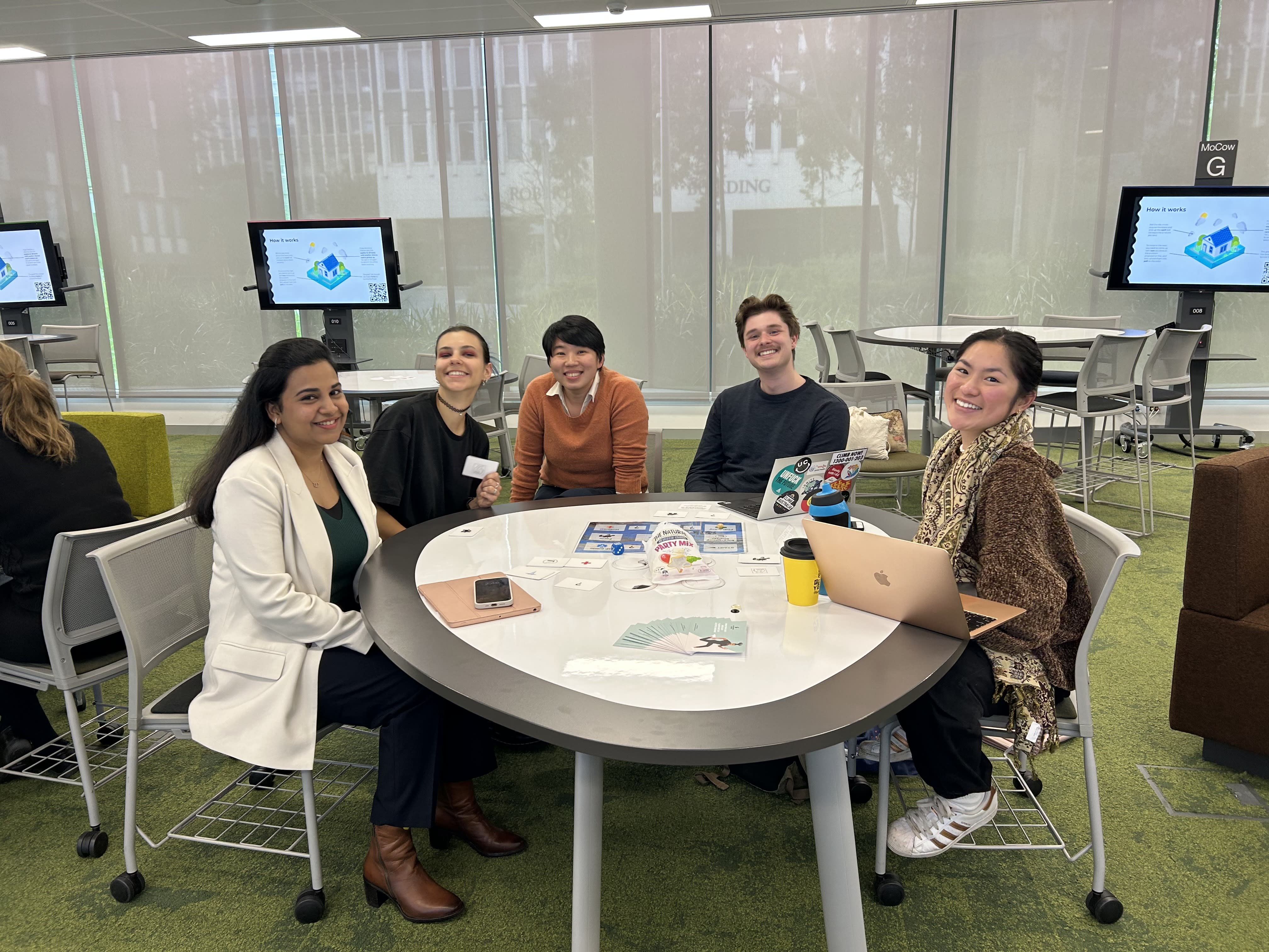 Monash University students sitting around a table playing Climate Disaster Response: The Game