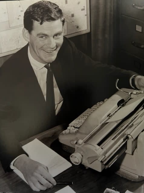 Mike McColl Jones smiling, sitting at his typrwriter