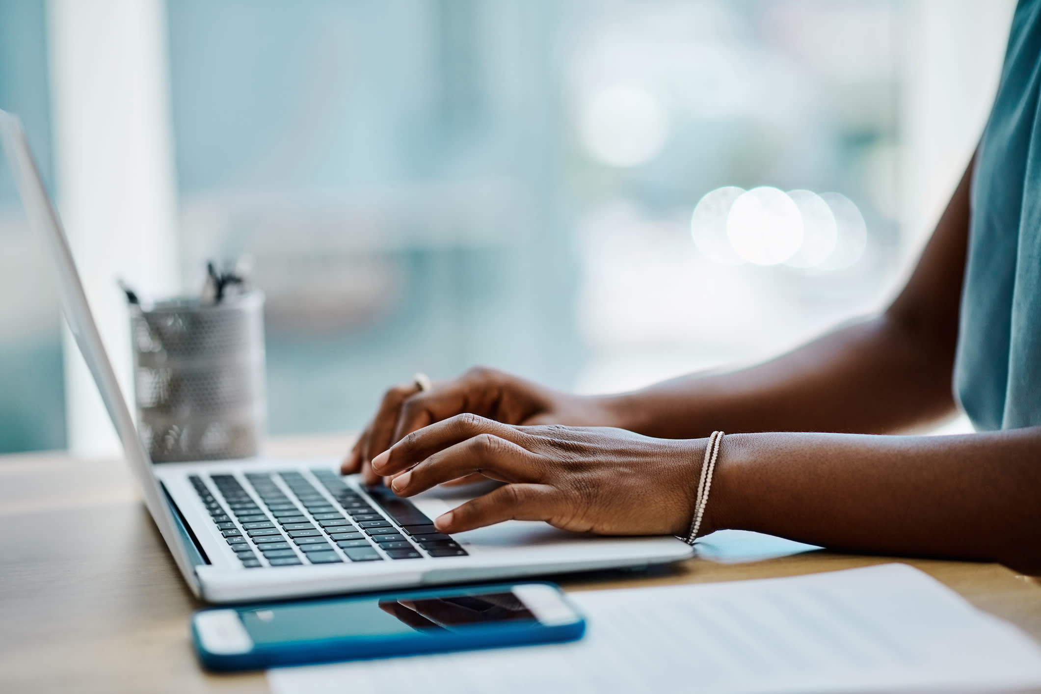 A black woman's hands typing on a laptop