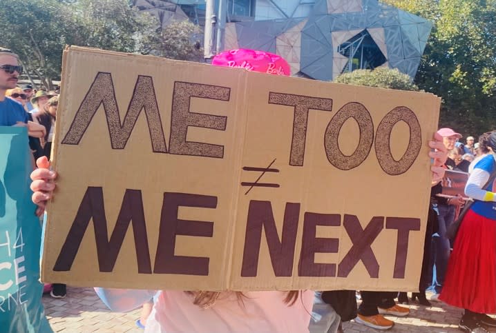 A girl holding a protest sign that reads “Me Too (does not equal Me Next