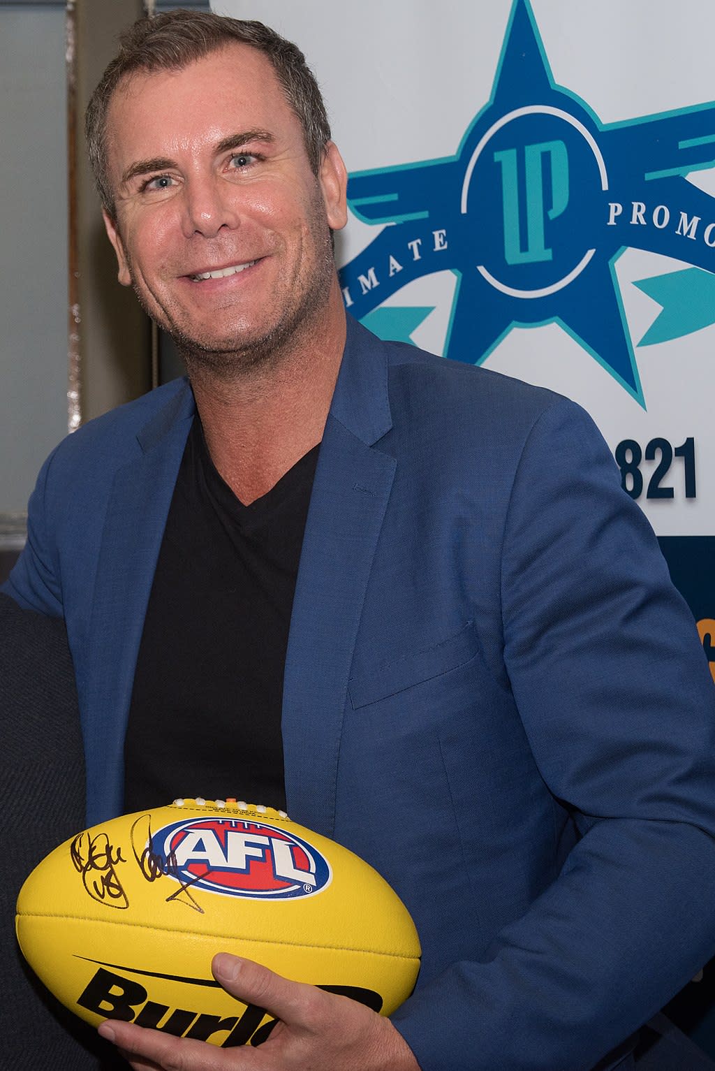 Former AFL premiership player Wayne Carey holding a football