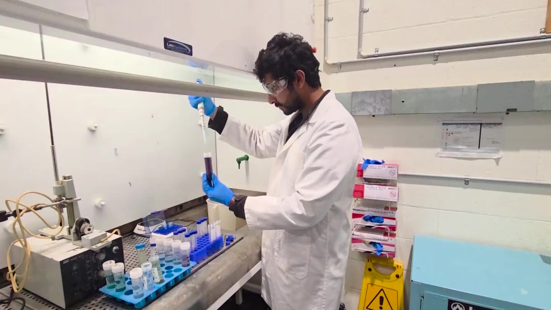 Scientist in a lab coat working with a pipette and test tubes