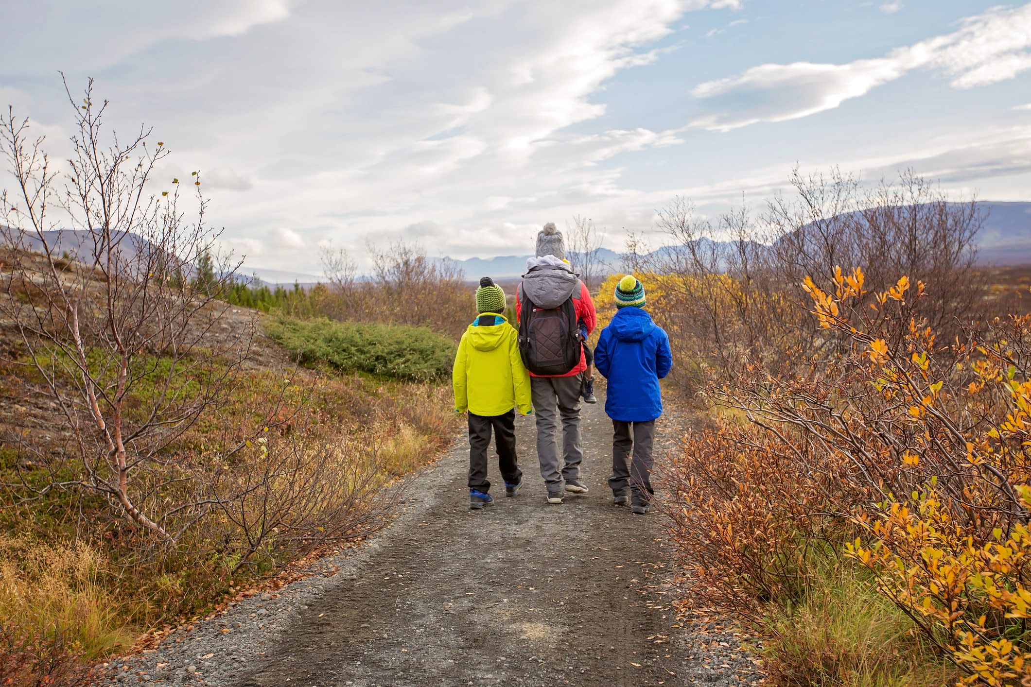 Photo from rear of a mother with children, walking on a path in scenic Thingvellir National Park rift valley, Iceland