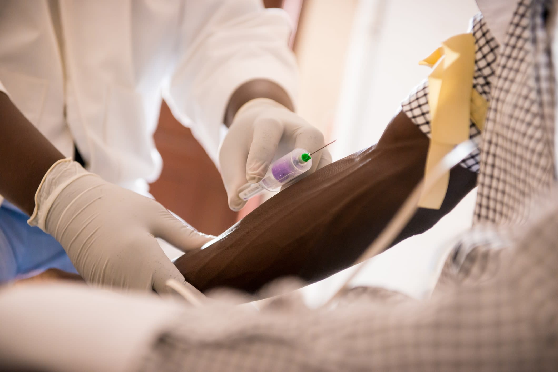 Doctor with needle about to draw blood from an African man