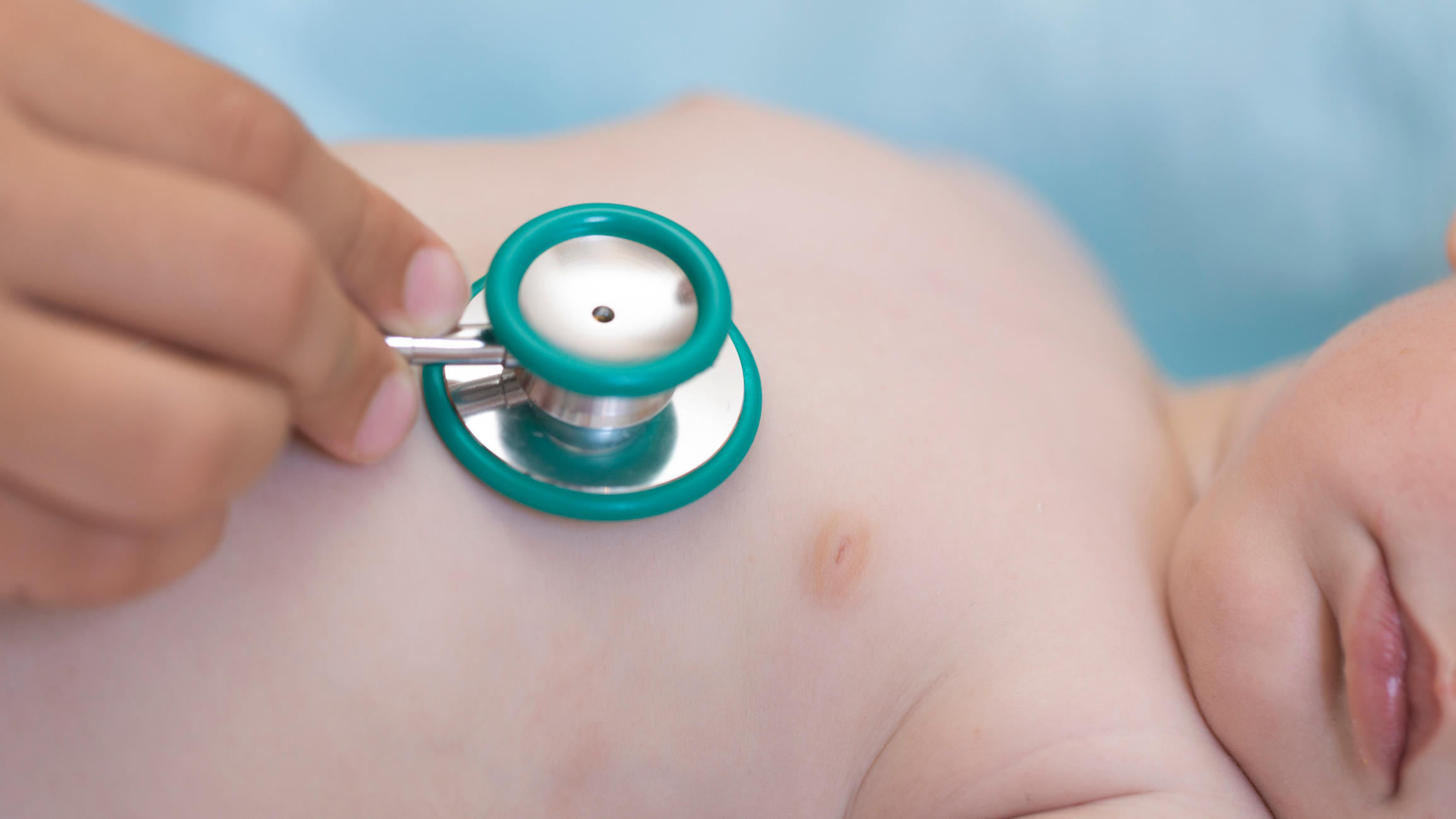 Close-up view of a pediatrician with a stethoscope examining a baby.