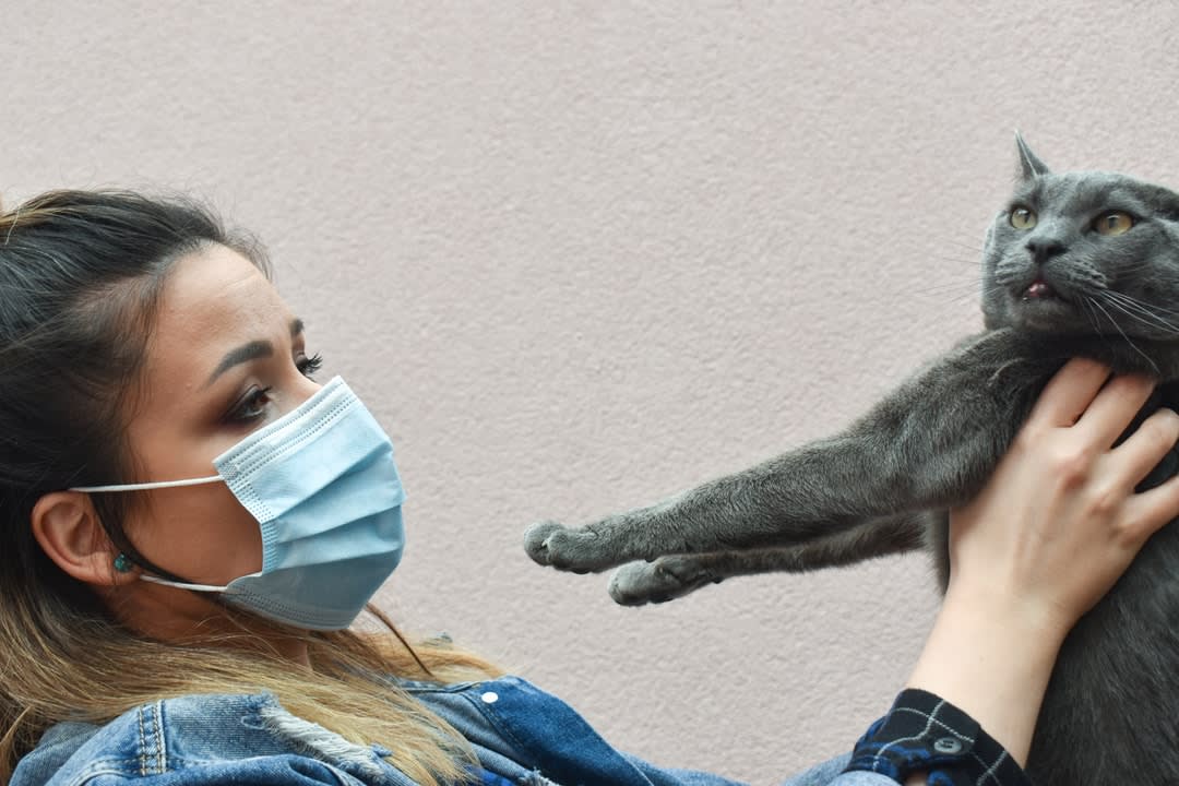 Masked woman holding cat during COVID-19 lockdown