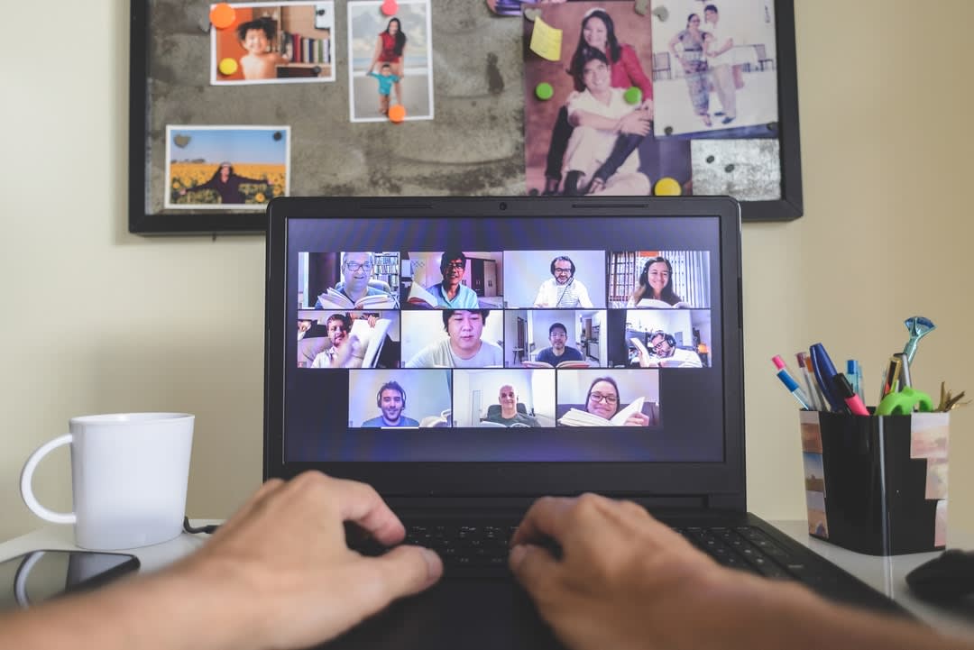 A man at his computer connects with people via zoom.