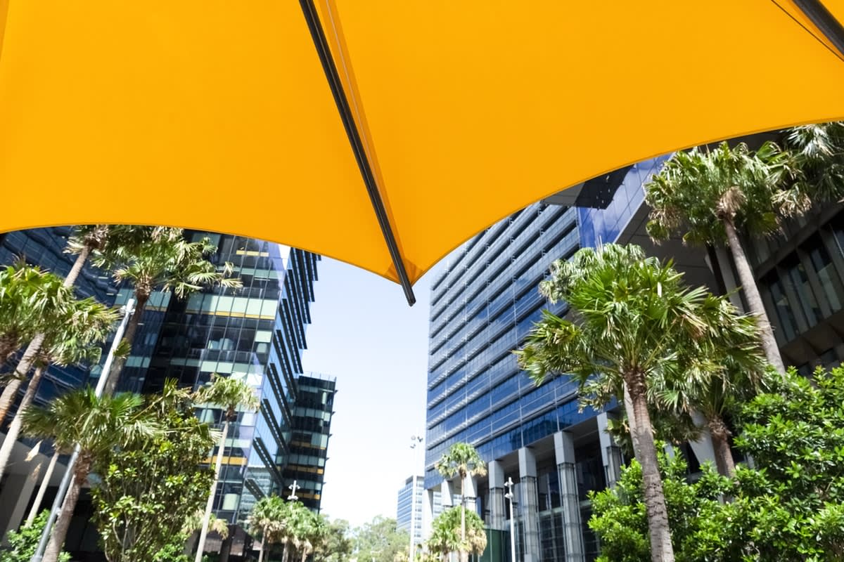 Photo taken from under sun shading of city buildings with surrounding trees