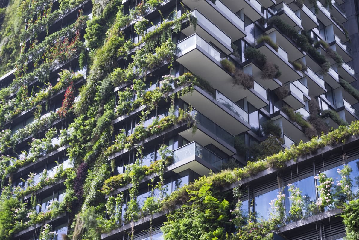 A modern apartment building with hanging vertical gardens on the sides