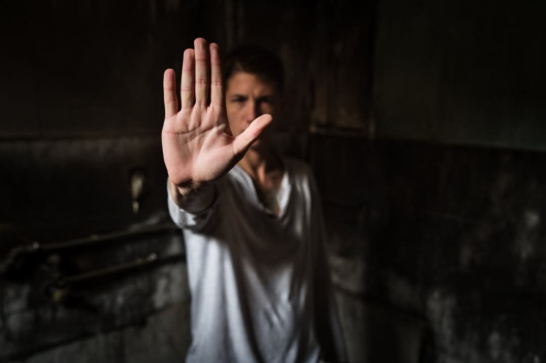 Young man showing STOP sign with his palm.