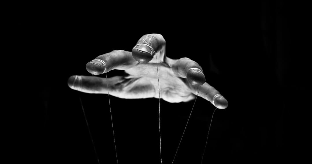 puppeteer hands controlling strings.