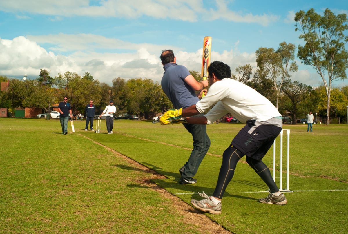 A group of men playing cricket in a park