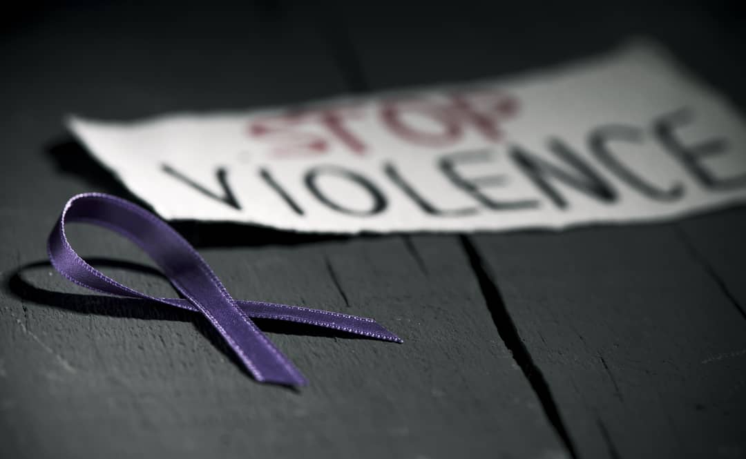 A purple awareness ribbon on a desk with a sign that says Stop Violence.