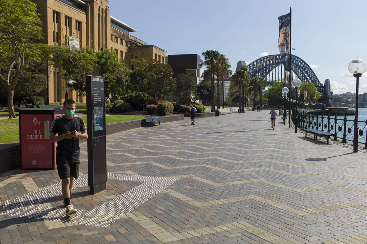 An all-but-deserted Sydney harbour waterfront with the Sydney Harbour Bridge in the background 