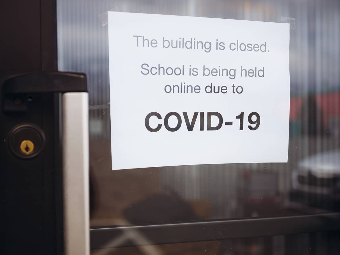 A sign on a door reading ‘Building is closed. School is being held online due to COVID-19'