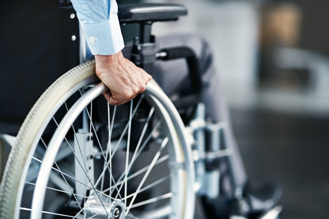 A man in a wheel chair with his hand on the wheel.