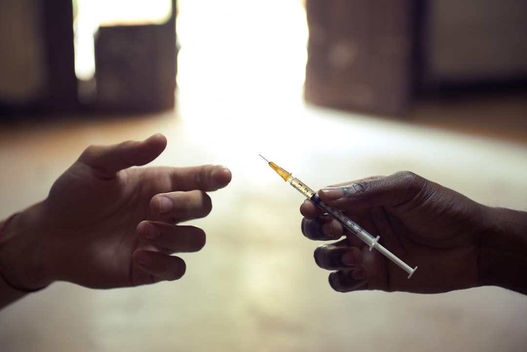 A person passes a needle to another person. 