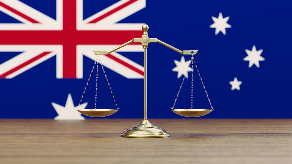 Gold-coloured justice scales with the Australian flag as a backdrop 