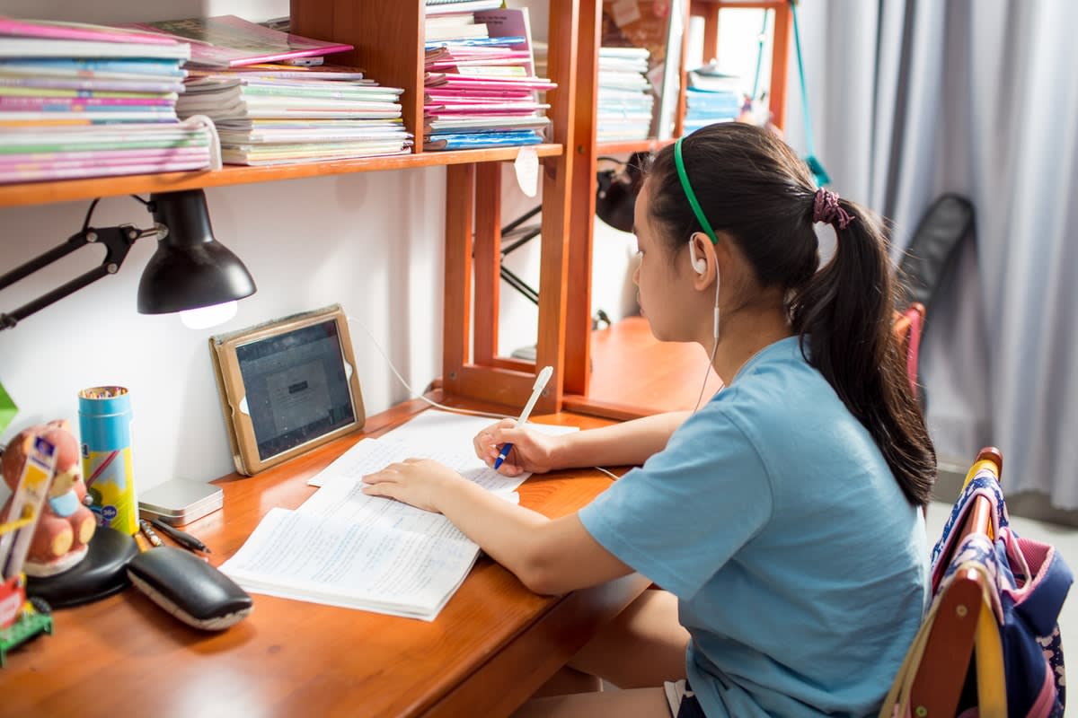 A Vietnamese girl sitting at her desk at home, studying/remote learning