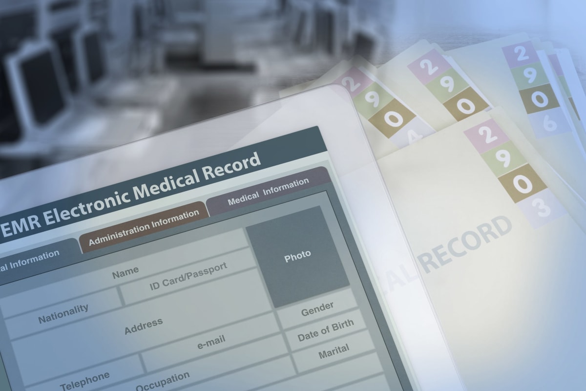 Depiction of an electronic medical record, with paper records in the background