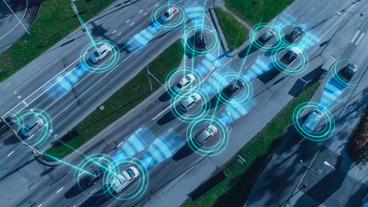 Top-down stylised image of an aerial drone over autonomous self-driving cars moving through a city.