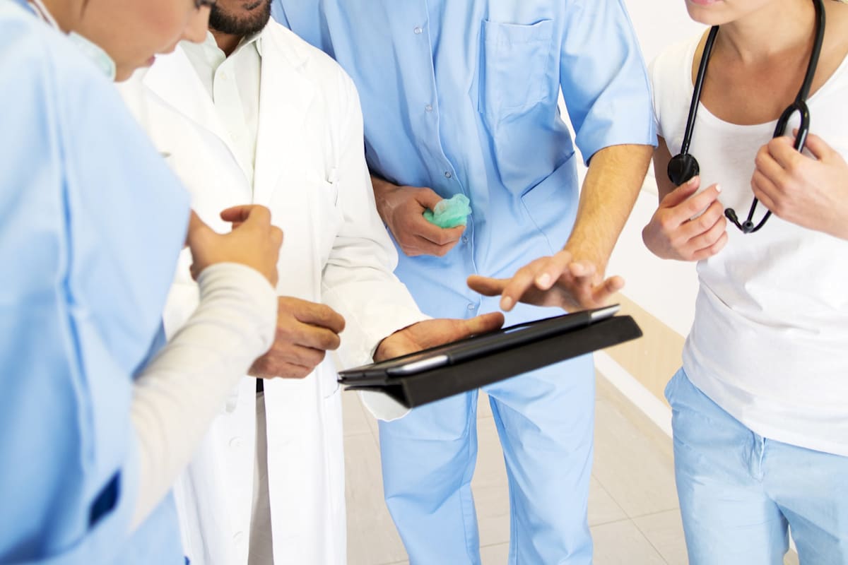 Group of healthcare workers in a hospital setting looking at digital tablet