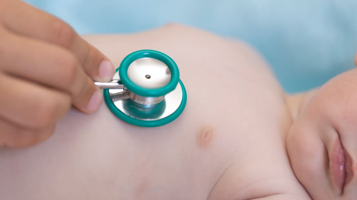 Close-up view of a pediatrician with a stethoscope examining a baby.