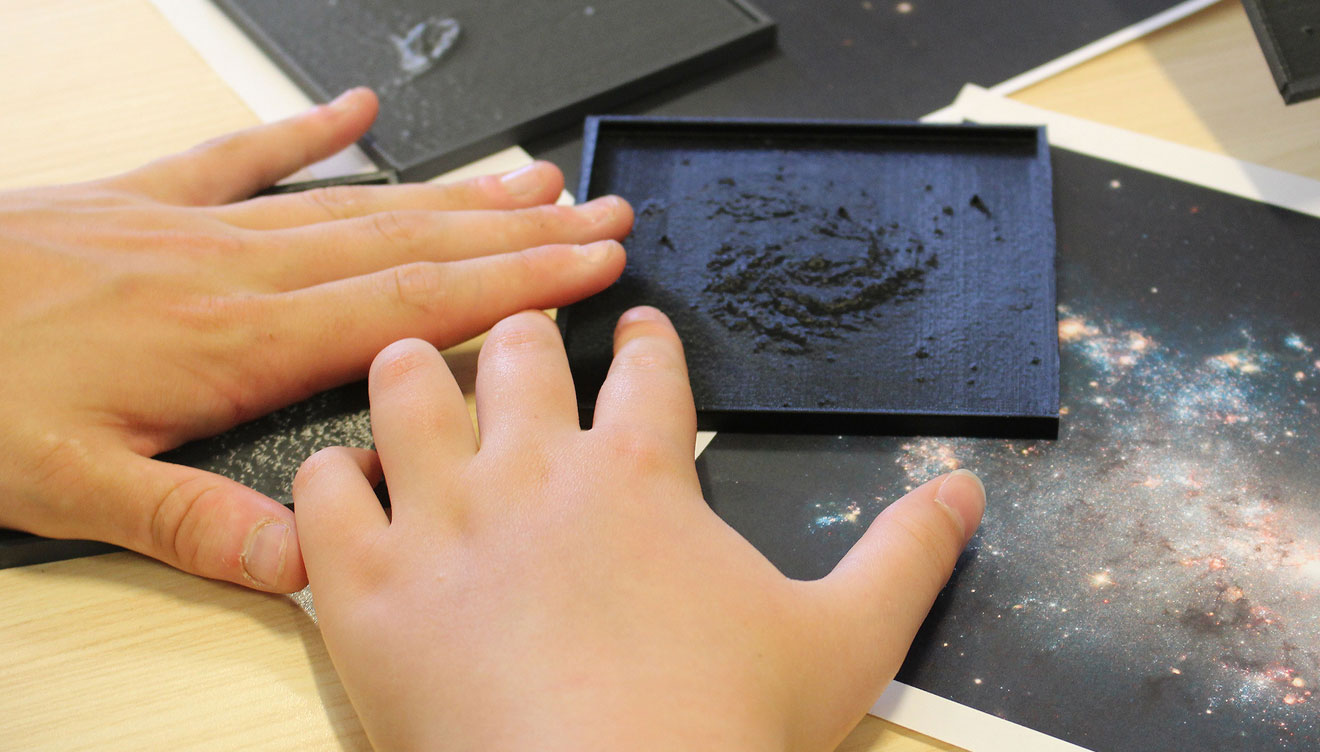 child touching 3d printed tile of galaxy