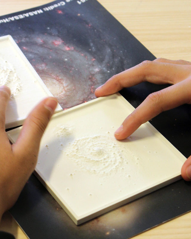 child touching 3d printed tile of space