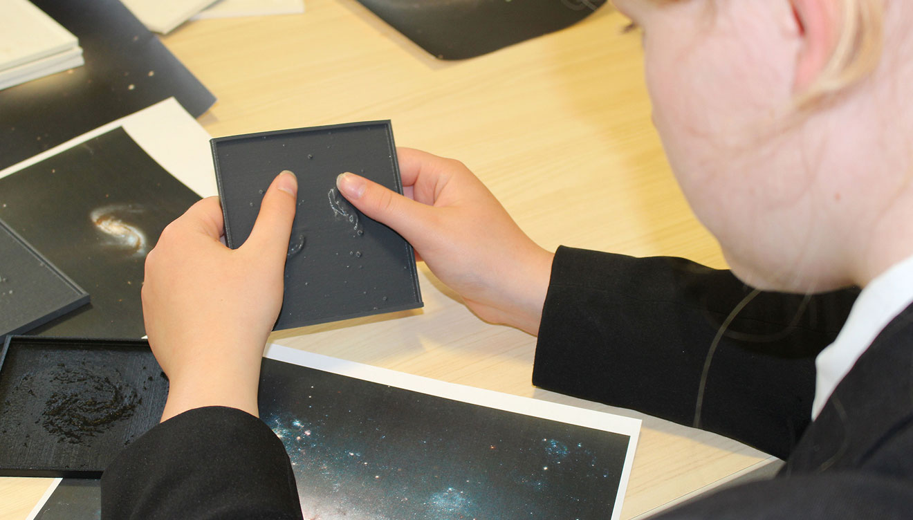 child touching 3d printed tile of space object