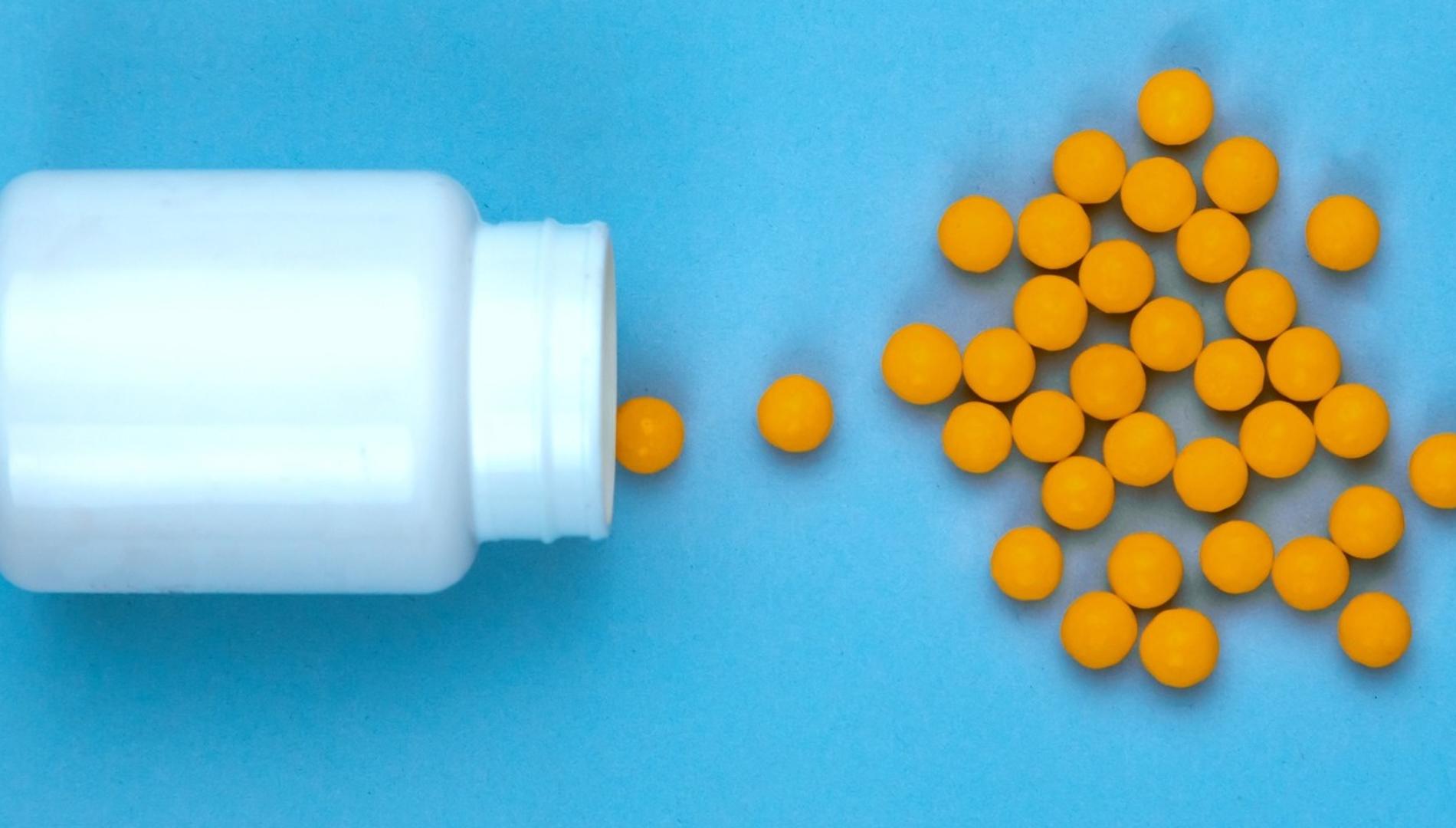 Yellow pills and plastic white bottle. Blue background