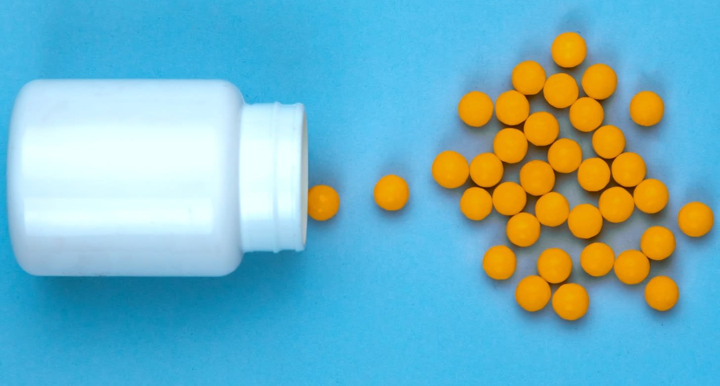 Yellow pills and plastic white bottle. Blue background