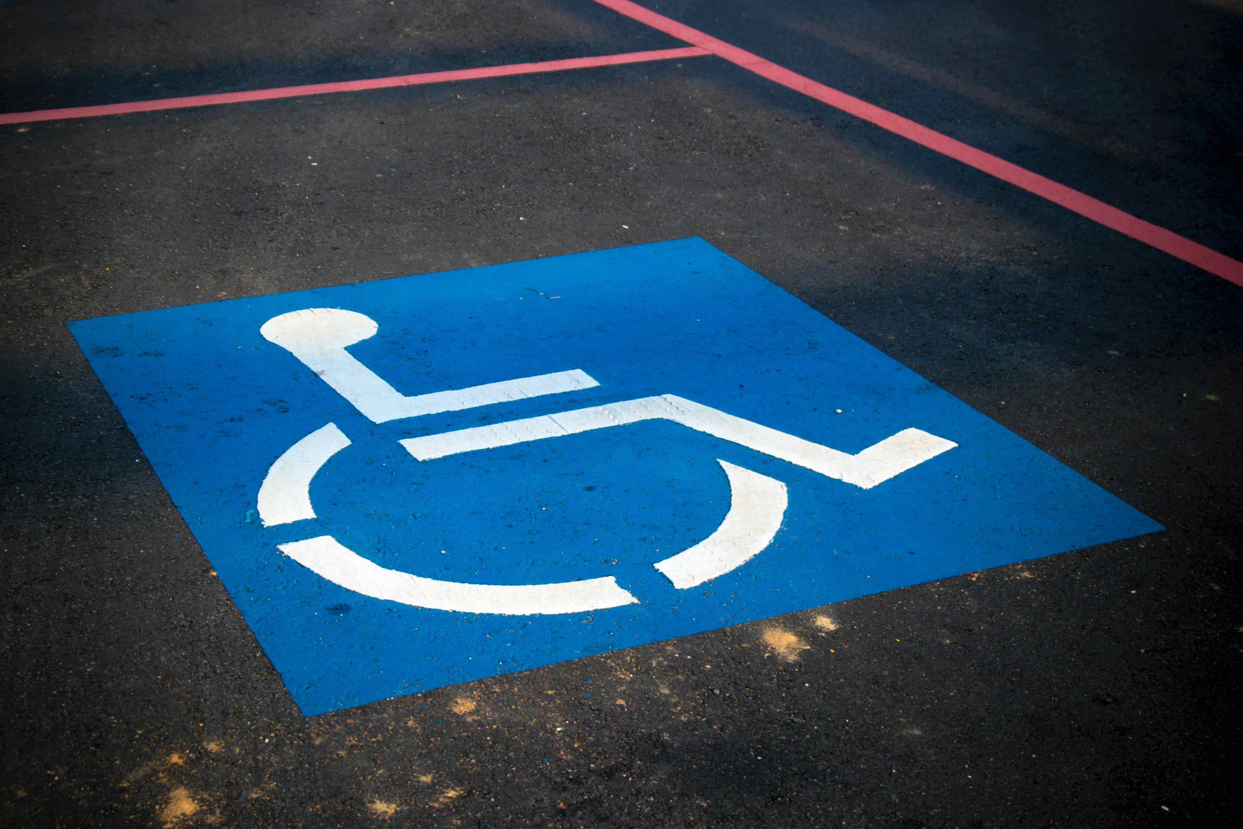 The symbol for a handicapped parking space with the blue square and white figure sitting in a wheelchair.