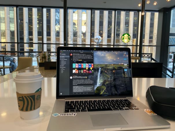 A view of the hotel from an area in the lobby that folks can relax and do remote work from in a small meeting area on the main lobby floor showing a cup of Starbucks coffee next to my MacBook Pro looking out at the street from the hotel into downtown Denver.