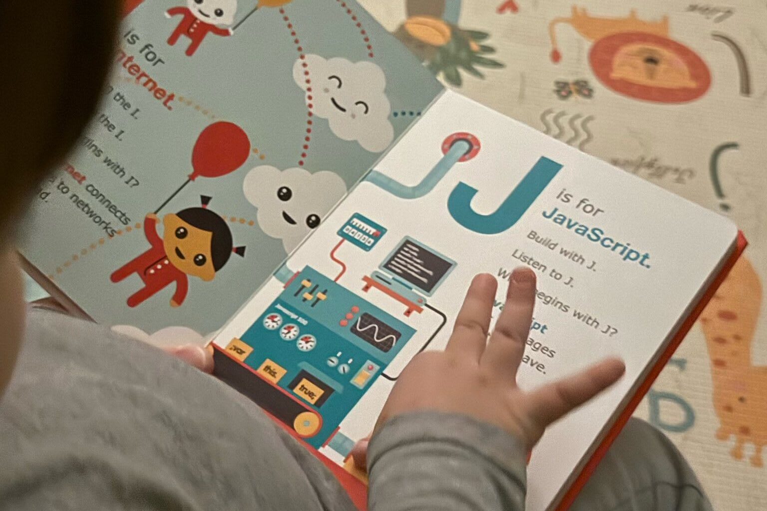 Child pointing to book that says J is for JavaScript