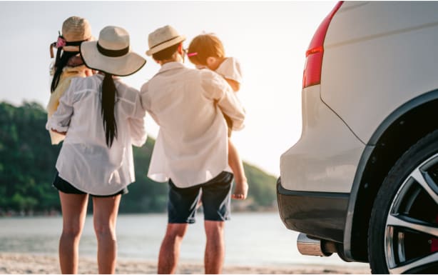 גבר ואישה עומדים ליד רכב ומחזיקים ילדים