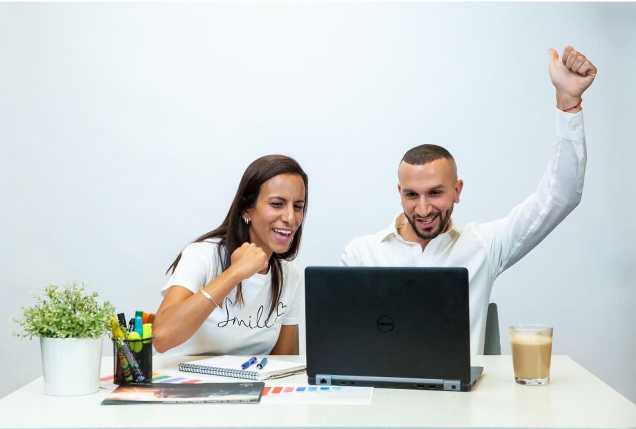 גבר ואישה יושבים עם מחשב נייד ומריעים