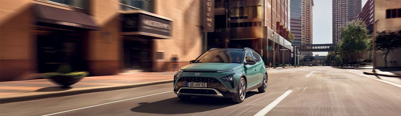 יונדאי באיון BAYON בצבע ירוק במהלך נסיעה בכביש עירוני - צילום חזית וצד הרכב