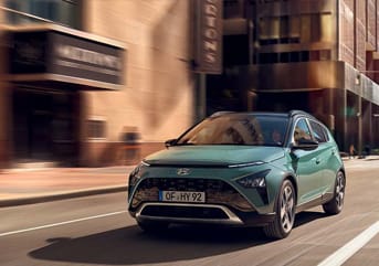 יונדאי באיון BAYON בצבע ירוק במהלך נסיעה בכביש עירוני - צילום חזית וצד הרכב