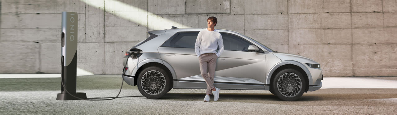 גבר נשען על רכב יונדאי איוניק 5 בזמן טעינה